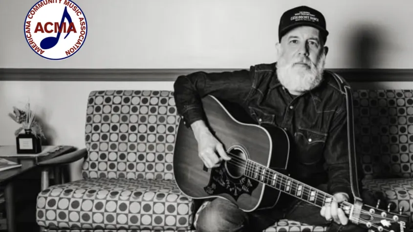 Musician sitting on couch with guitar; ACMA logo in corner