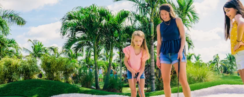 a mom and her 2 daughters play mini golf
